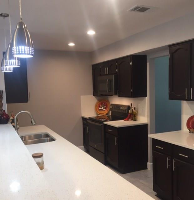 3305 Spaniel Drive Austin, TX 78759 - Photo 20 of 20 A contemporary kitchen showcasing dark cabinetry, luminous white countertops, and modern pendant lighting.