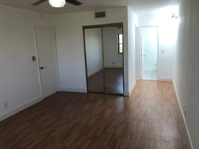 9273 Southwest 8th Street, Unit 417 Boca Raton, FL 33428 - Photo 13 of 25 an empty room with wooden floor and mirror