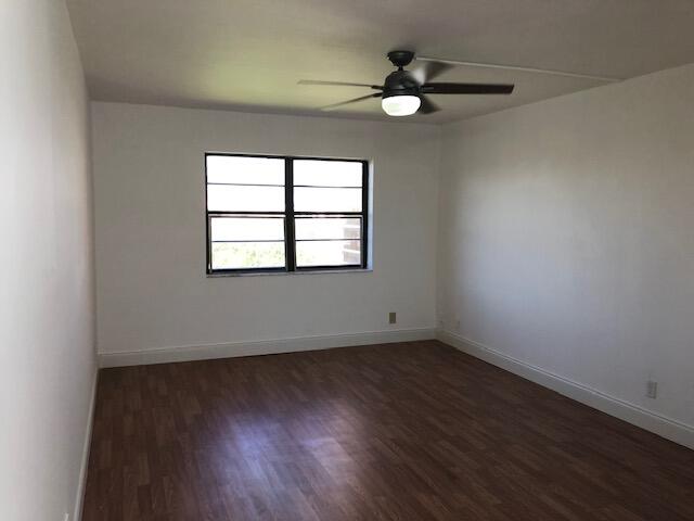 9273 Southwest 8th Street, Unit 417 Boca Raton, FL 33428 - Photo 14 of 25 an empty room with wooden floor fan and windows