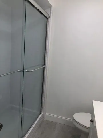 a bathroom with a granite countertop toilet and a shower