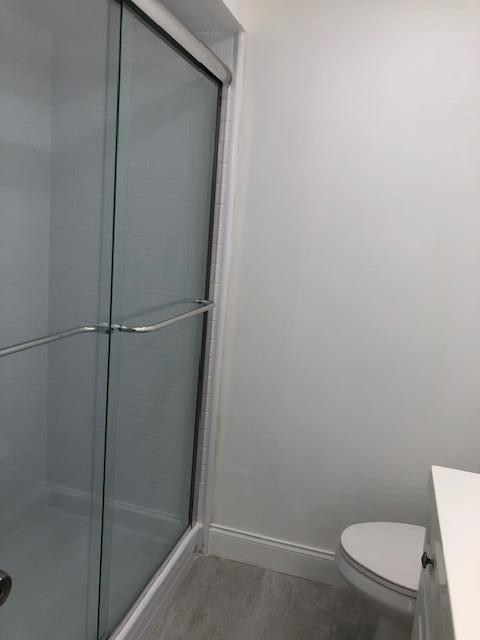 9273 Southwest 8th Street, Unit 417 Boca Raton, FL 33428 - Photo 17 of 25 a bathroom with a granite countertop toilet and a shower