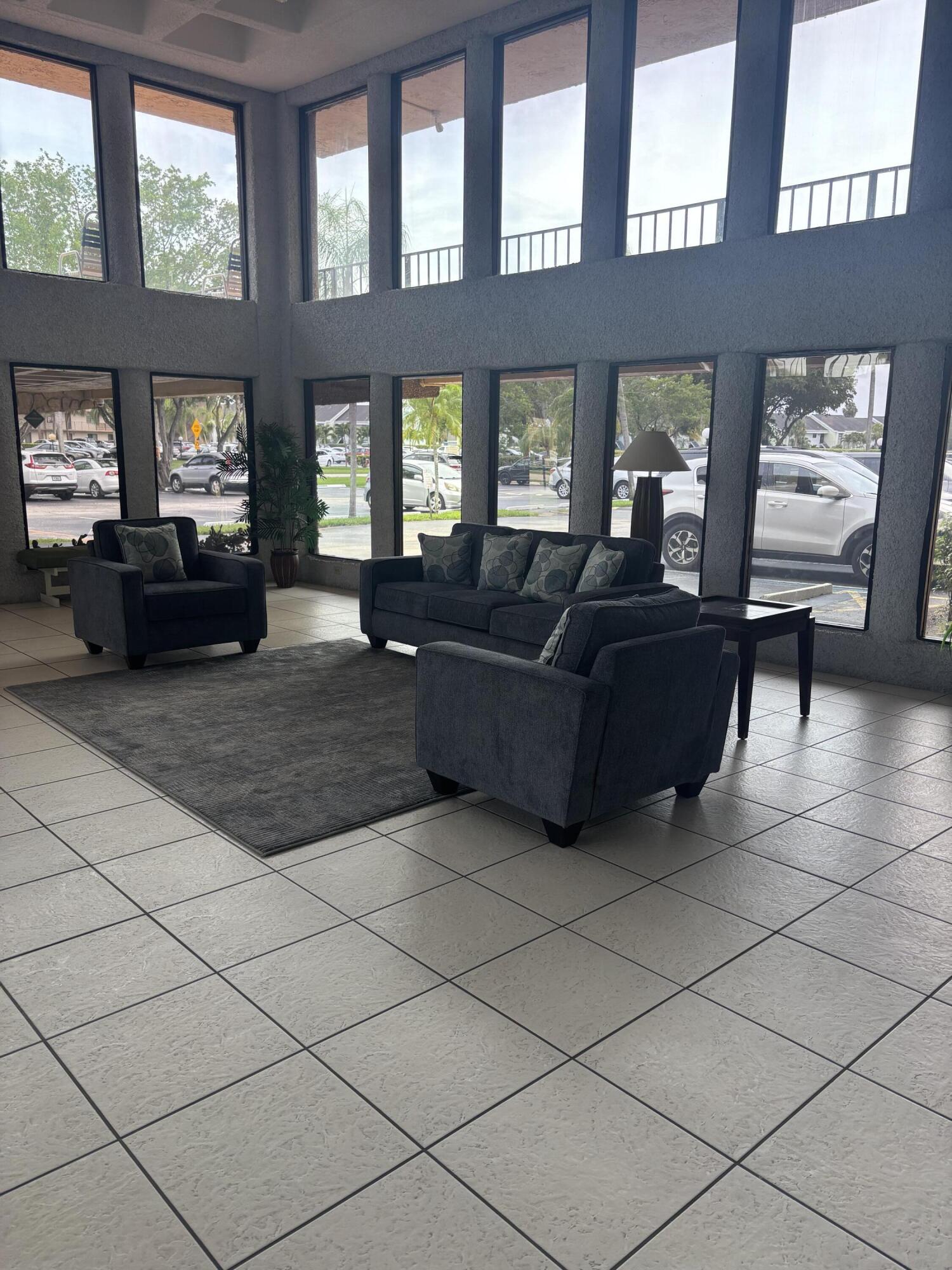 9273 Southwest 8th Street, Unit 417 Boca Raton, FL 33428 - Photo 5 of 25 a living room with furniture and windows