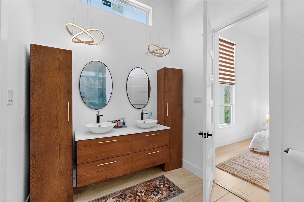 3946 North Cresthaven Road Dallas, TX 75209 - Photo 24 of 38 Modern vanity featuring dual vessel sinks, wall-mounted faucets, and two oval framed mirrors