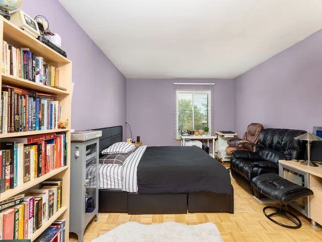 a bedroom with a bed and a computer on a desk next to a window