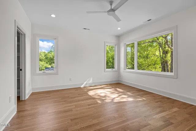 an empty room with wooden floor and windows