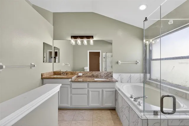 a spacious bathroom with a granite countertop sink a mirror and a bathtub