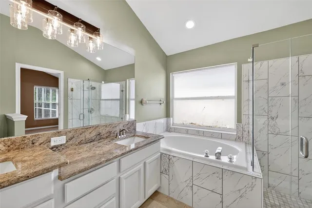 a bathroom with a granite countertop bathtub a sink and a large mirror