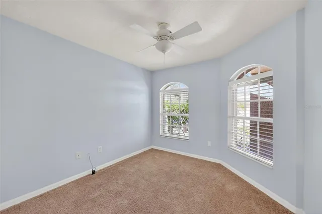 an empty room with windows and ceiling fan
