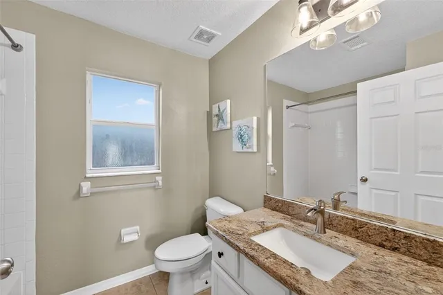 a bathroom with a granite countertop sink a toilet and a mirror
