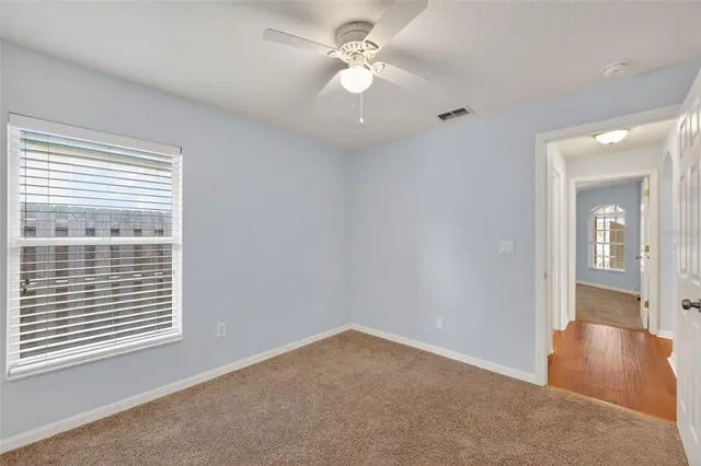 an empty room with windows and fan