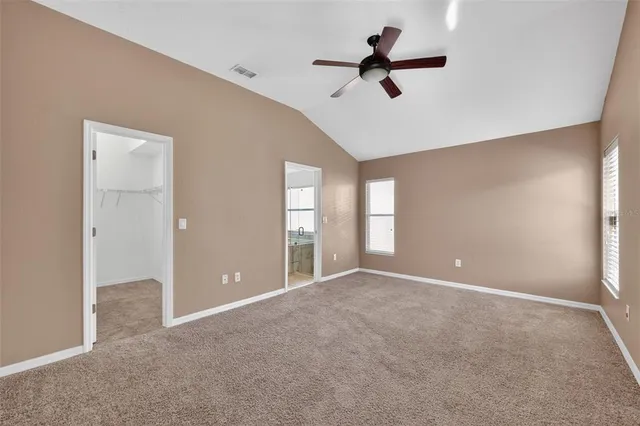 a view of an empty room with a ceiling fan and window