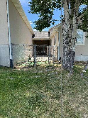 641 East Greystone Way Tooele, UT 84074 - Photo 25 of 30 Grassed side yard featuring a chain-link fence and a covered patio area