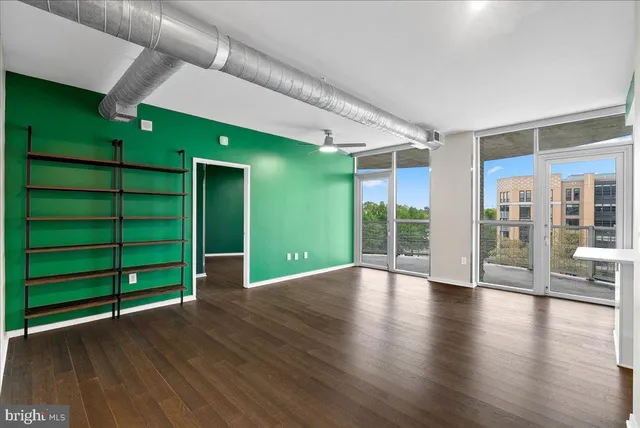 an empty room with wooden floor windows and entryway