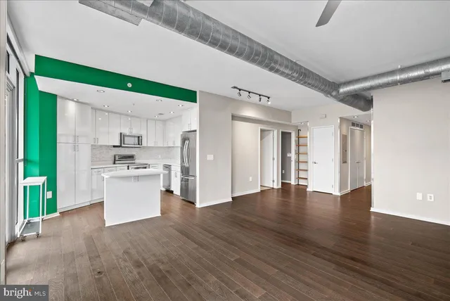 a view of kitchen with stainless steel appliances granite countertop a refrigerator oven a sink dishwasher and white cabinets with wooden floor