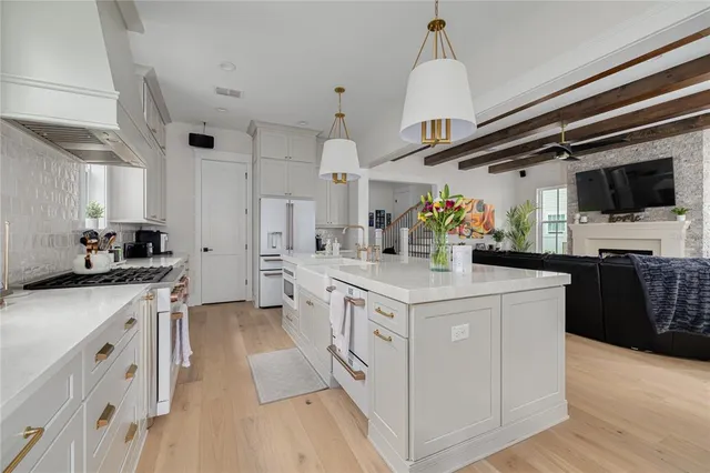 a kitchen with stainless steel appliances a stove top oven a sink dishwasher and a refrigerator with wooden floor