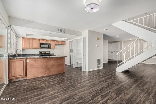 a kitchen with stainless steel appliances granite countertop a refrigerator a stove and a wooden floors