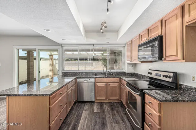 a kitchen with granite countertop stainless steel appliances a sink stove top oven and cabinets
