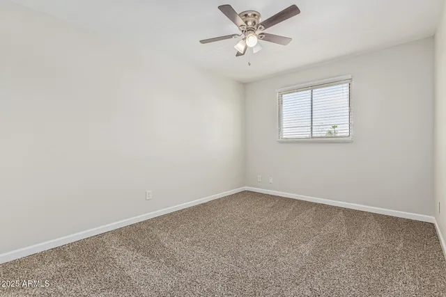 an empty room with a window and a fan