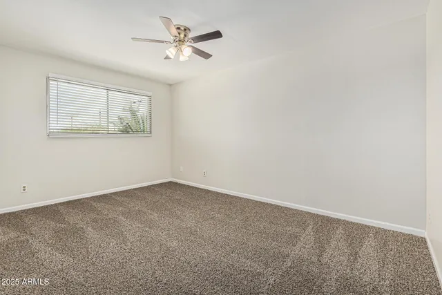 an empty room with a window and a fan