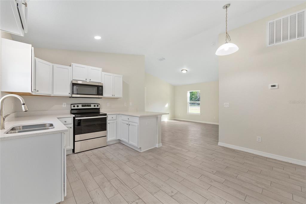 360 Locust Road Ocala, FL 34472 - Photo 18 of 48 a kitchen with granite countertop a stove a sink and a refrigerator