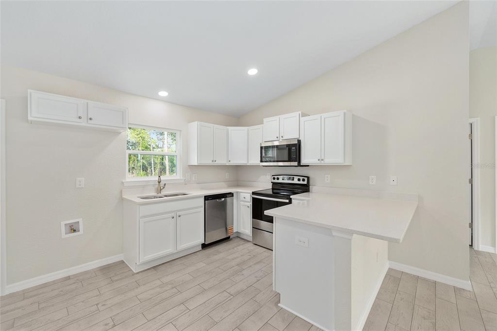360 Locust Road Ocala, FL 34472 - Photo 20 of 48 a kitchen with stainless steel appliances a white stove top oven sink and cabinets