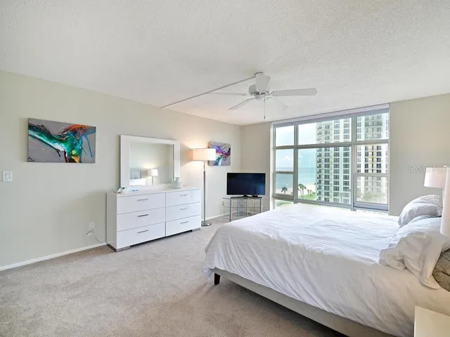 a spacious bedroom with a large bed and a flat tv screen