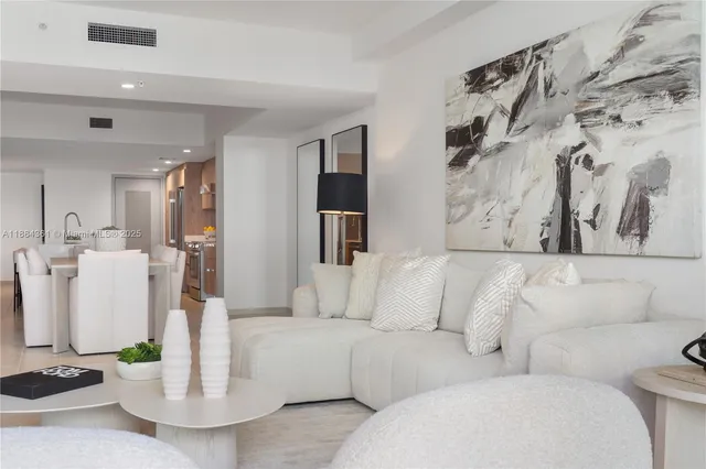 a living room with furniture a flat screen tv and kitchen view