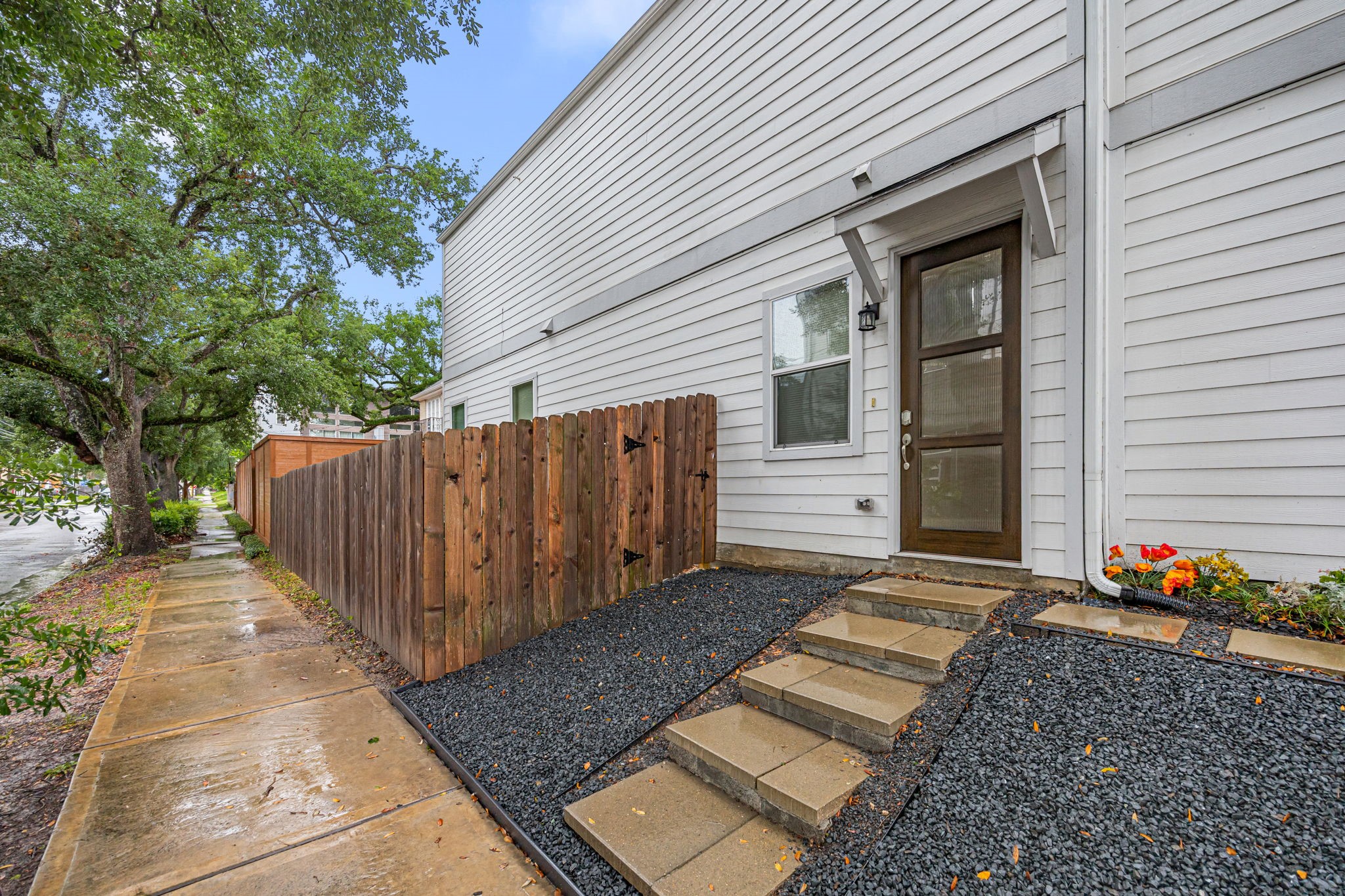 1732 Wichita Street Houston, TX 77004 - Photo 2 of 35 Private side entrance with modern wood and glass front door, custom stepping stone walkway, decorative black star gravel landscaping, and gated access to your backyard.