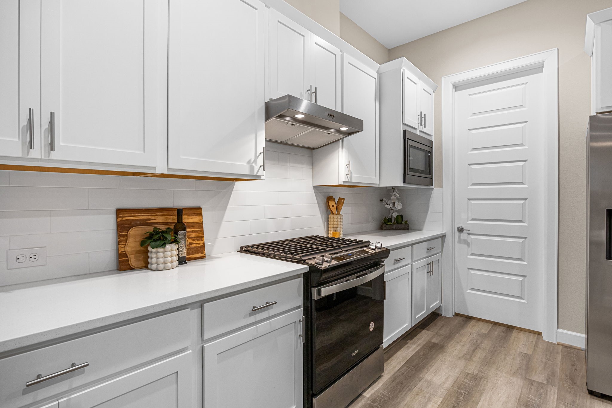 1732 Wichita Street Houston, TX 77004 - Photo 8 of 35 Modern kitchen design with gas range, sleek vent hood, subway tile backsplash, built-in microwave, and contemporary shaker-style cabinetry.
