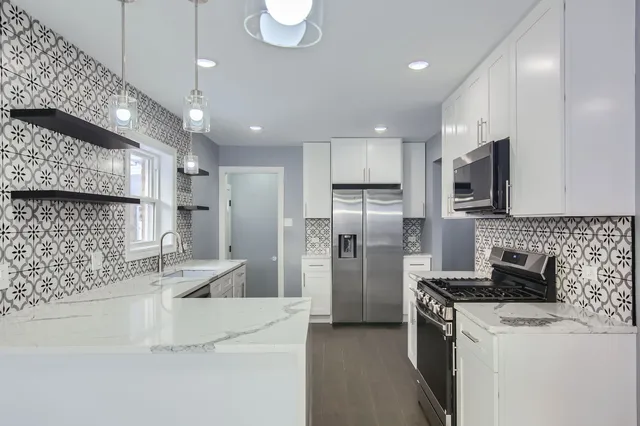 a kitchen with stainless steel appliances granite countertop a sink a stove a refrigerator and a oven with wooden floor