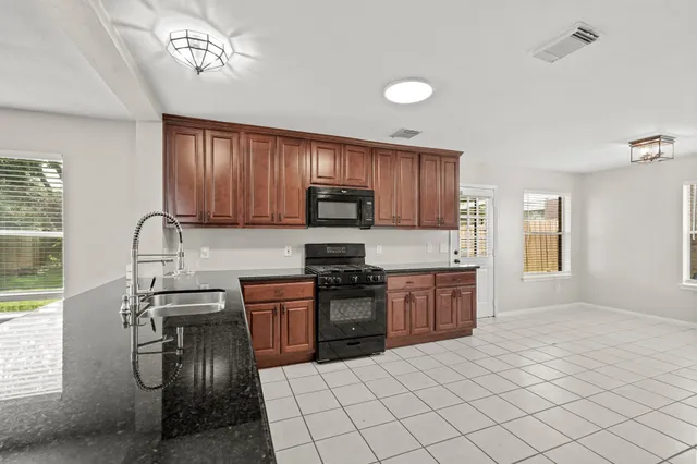 a kitchen with granite countertop a sink stainless steel appliances and cabinets