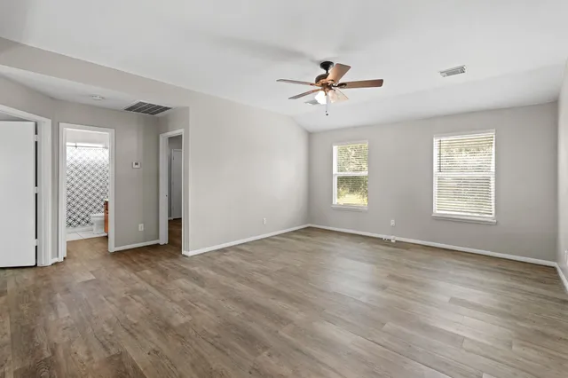 a view of an empty room with a window and wooden floor