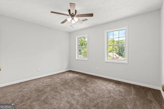 an empty room with windows and fan