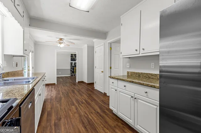 a view of a kitchen with granite countertop wooden cabinets and white appliances