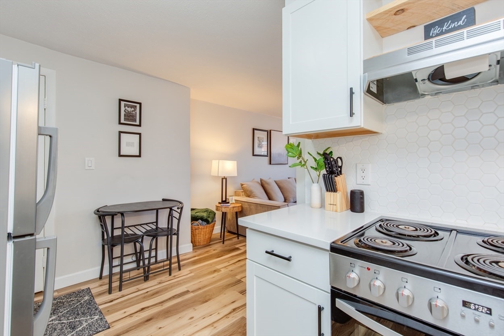 15 Staples Avenue, Unit 46 Everett, MA 02149 - Photo 5 of 35 a kitchen with stainless steel appliances a stove a table and chairs with wooden floor