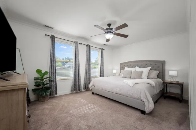 a bedroom with a large bed and a flat tv screen on dresser