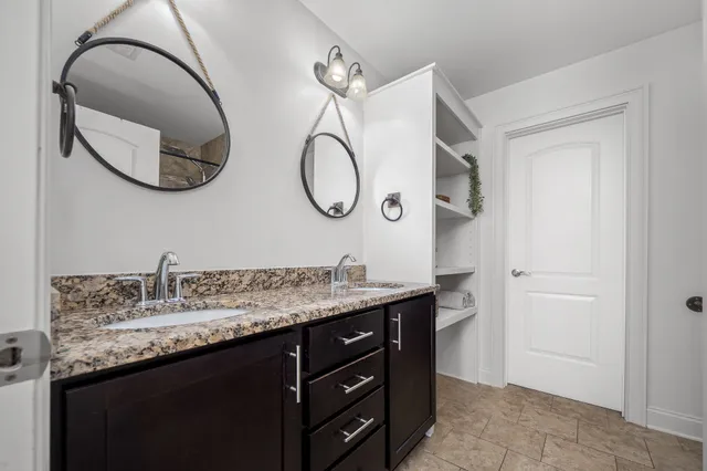 a bathroom with a granite countertop double vanity sink and a mirror