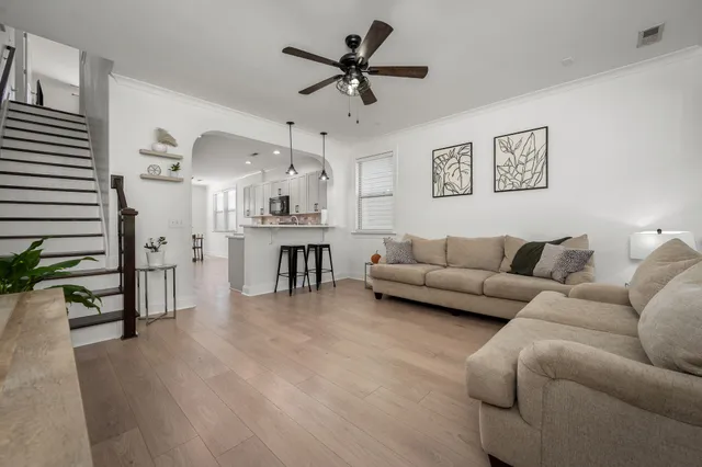 a living room with furniture kitchen view and a chandelier