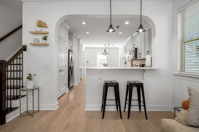 a kitchen with kitchen island stainless steel appliances a table chairs refrigerator and sink