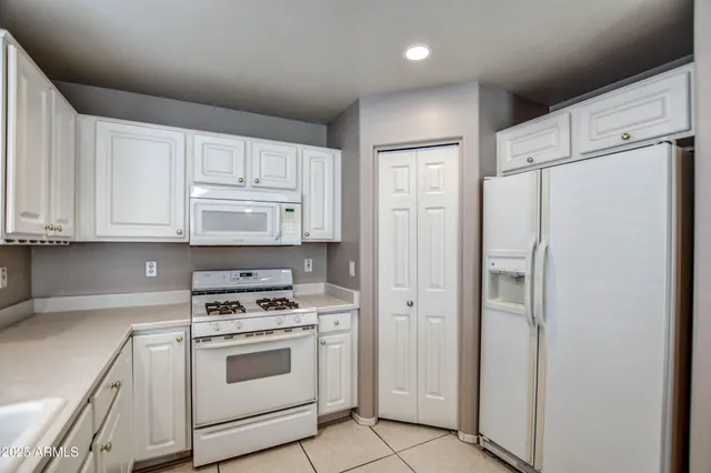 a kitchen with white cabinets and white appliances