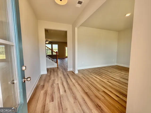 a view of a hallway with wooden floor and a bathroom