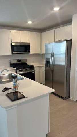 a kitchen with stainless steel appliances a refrigerator a sink a stove a microwave and cabinets