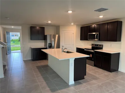 a large kitchen with stainless steel appliances a stove top oven a sink dishwasher and a refrigerator with wooden floor