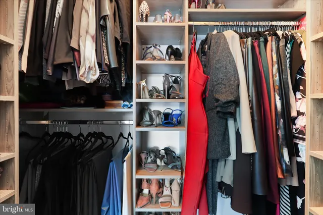 a view of walk in closet with clothes and shoes
