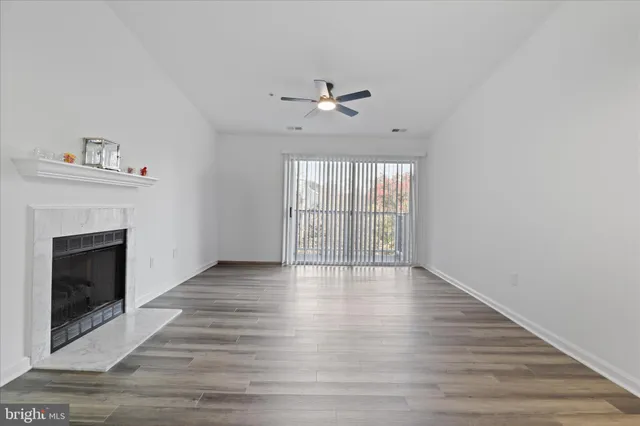 an empty room with wooden floor fireplace and windows