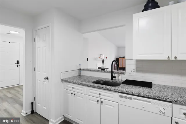 a kitchen with granite countertop white cabinets and sink