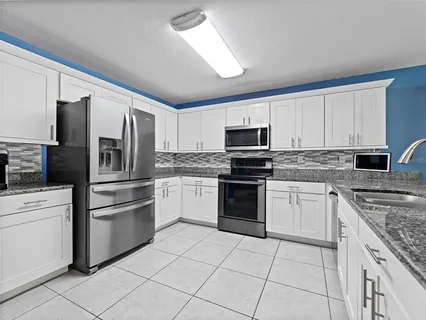 a kitchen with granite countertop a refrigerator sink and stove