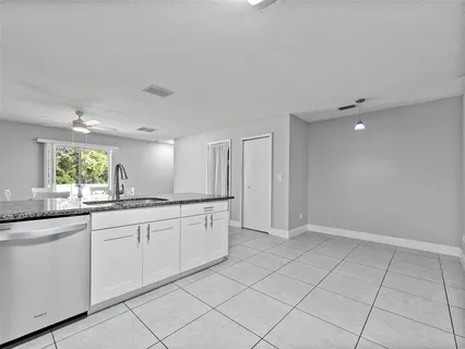 a large white kitchen with a sink and dishwasher with a large window