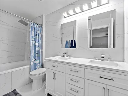 a bathroom with a double vanity sink toilet mirror and bathtub