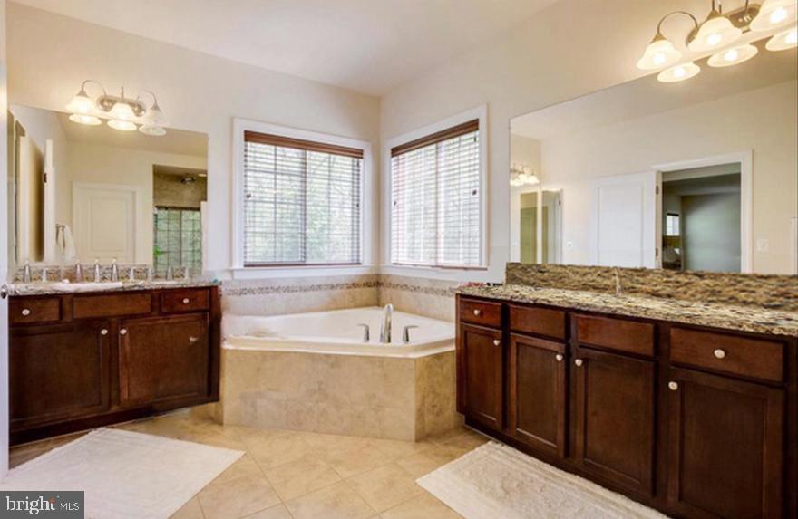 1299 Scotts Run Road McLean, VA 22102 - Photo 13 of 22 a spacious bathroom with a granite countertop tub a double vanity sink and a large mirror